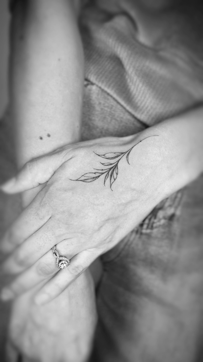 Delicate fine line leaf branch on hand